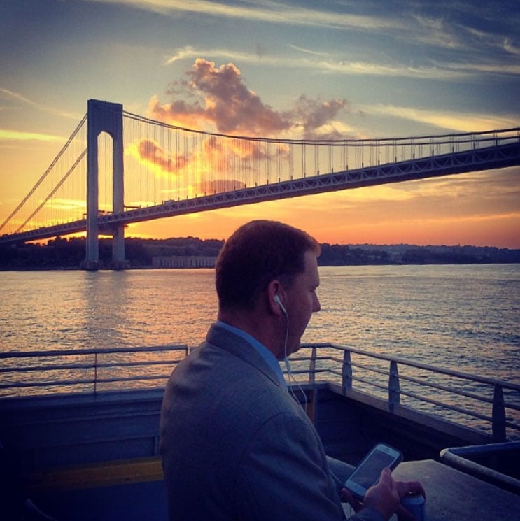 A man enjoys listening to music on his headphones on the ferry while the sun sets in the background