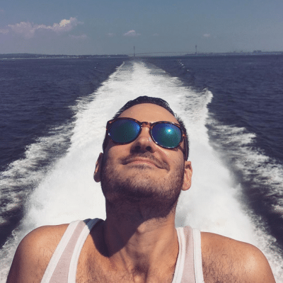 A selfie of a young man on the stern of the boat with the wake in the background