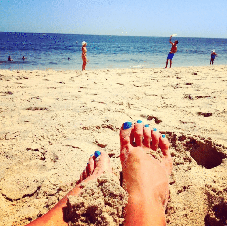 Painted toes in the sand overlooking the beach