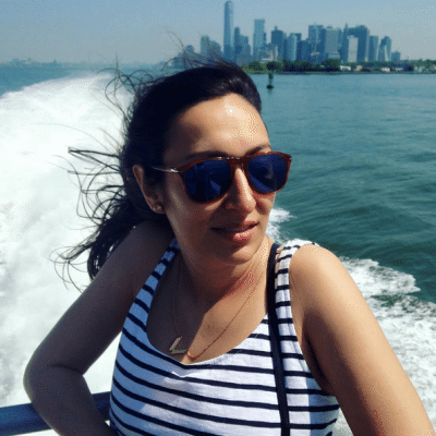 A woman wearing sunglasses on the ferry with Manhattan in the background