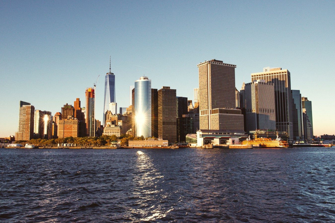 The sun glinting off the skyscrapers of lower Manhattan while viewed from the deck of a Seastreak Ferry