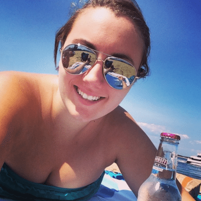 A selfie of a young woman on the beach wearing sunglasses