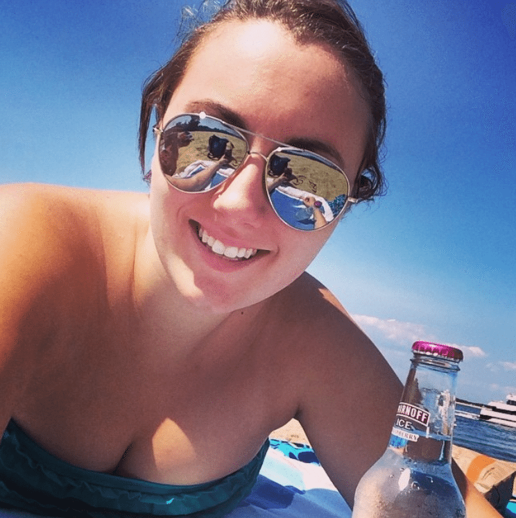 A selfie of a young woman on the beach wearing sunglasses