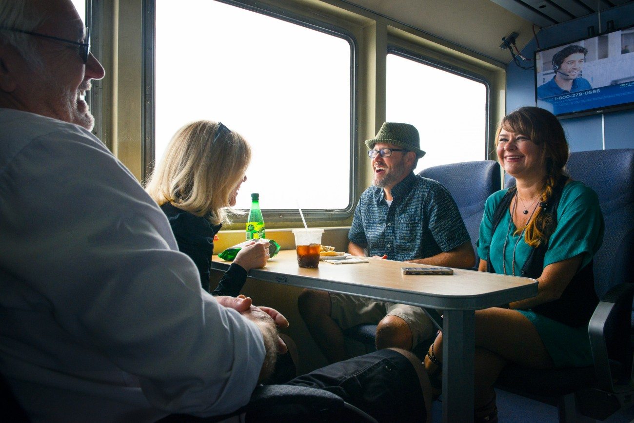 Friends enjoy the ride as they eat snacks around a table on the ferry