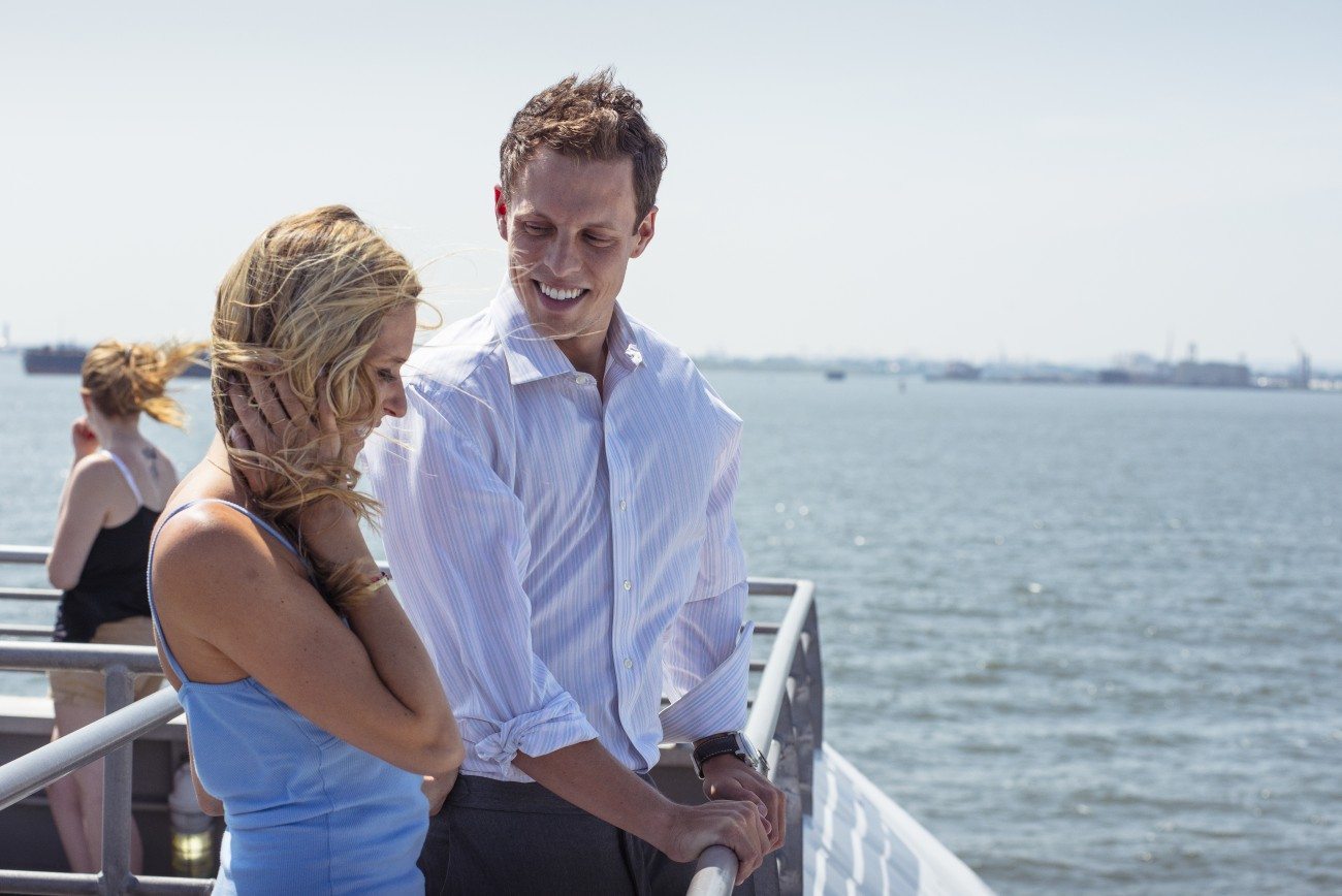 Couple looks out over the water from the deck of the ferry on a sunny day.