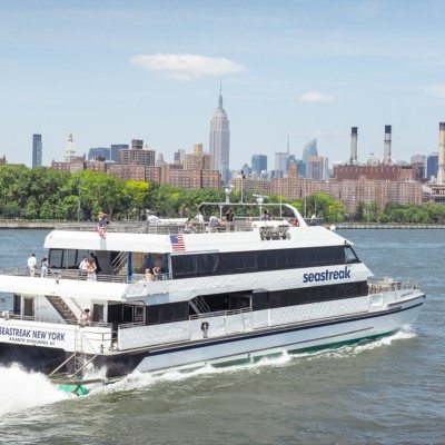 Seastreak Ferry cruising through the harbour with scenic views of New York City behind it.