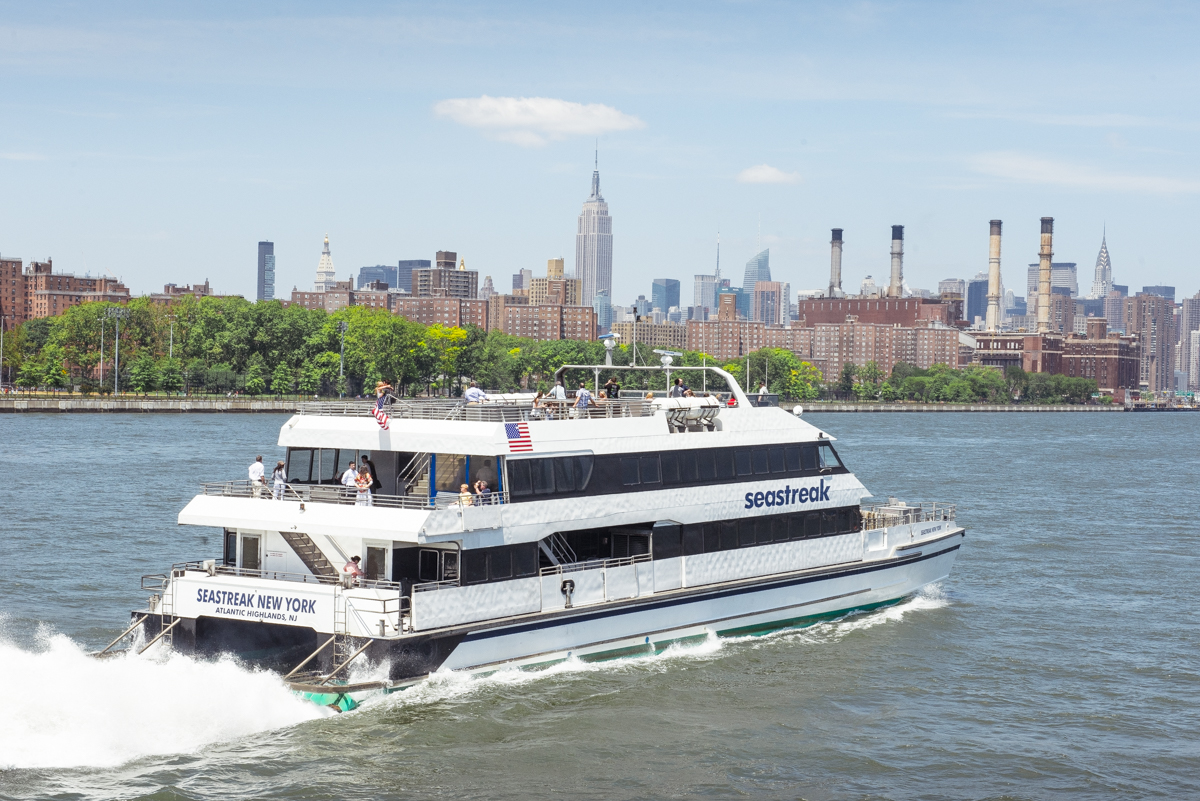 Seastreak Ferry cruising through the harbour with scenic views of New York City behind it.